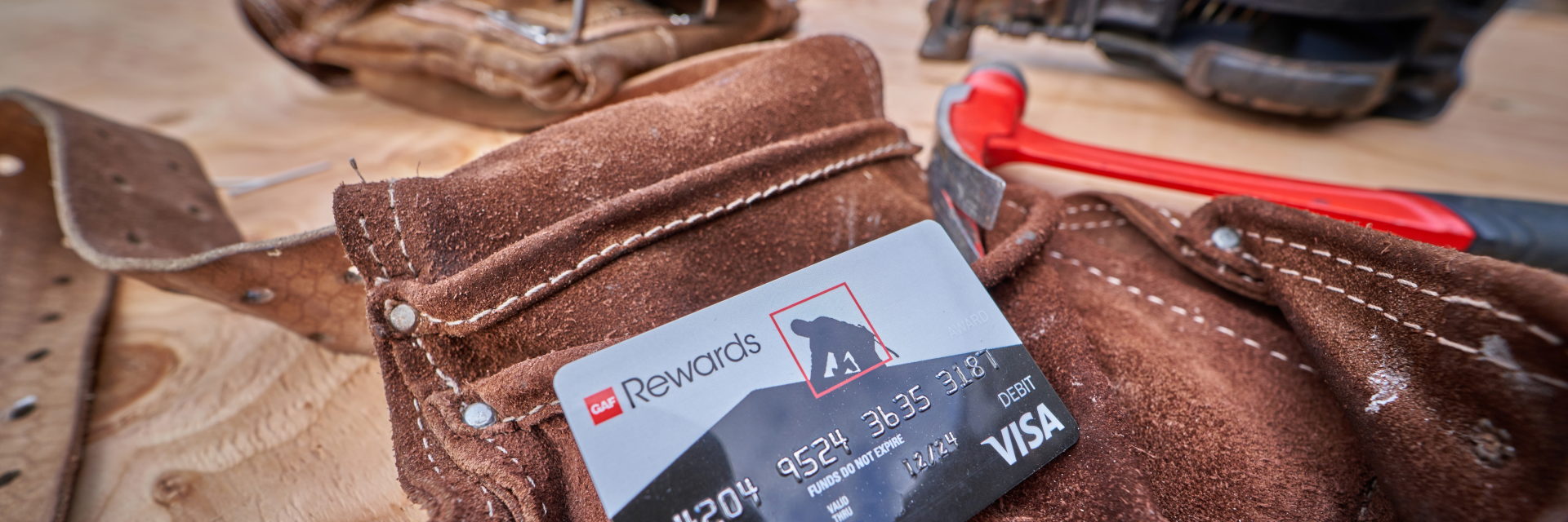 GAF Rewards gift card for contractor rewards program on top of tool belt and hammer